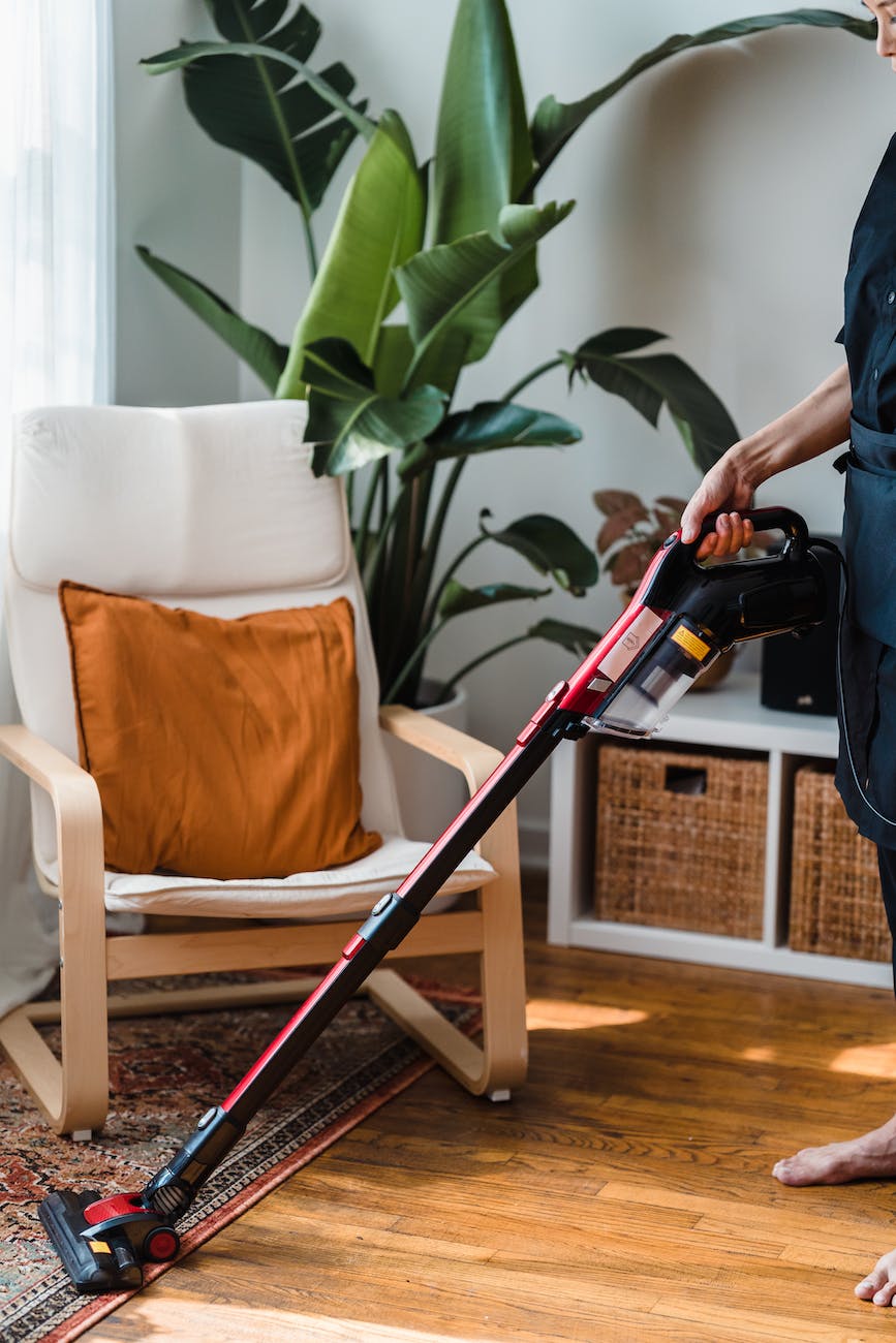 person in black t shirt and black pants holding black and red vacuum cleaner