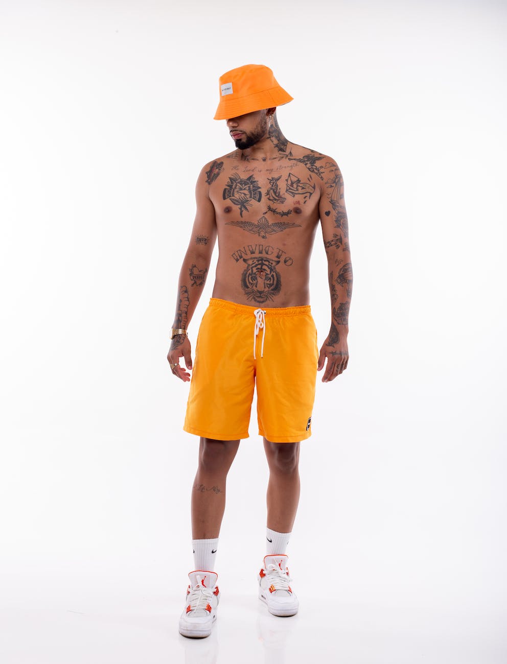 topless man in yellow shorts and bucket hat